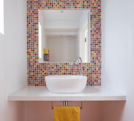 Contemporary bathroom with wash basin, colorful glass mosaic tiles, painted MDF shelf and mirror...