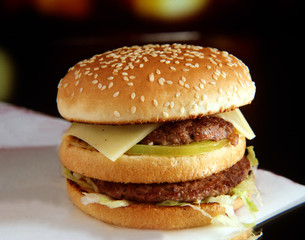 Panecillo de semillas con dos hamburguesas, lechuga, tomate y queso.