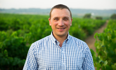 Naklejka na ściany i meble Male farmer standing near grapes in vineyard at summertime