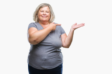 Senior plus size caucasian woman over isolated background amazed and smiling to the camera while presenting with hand and pointing with finger.