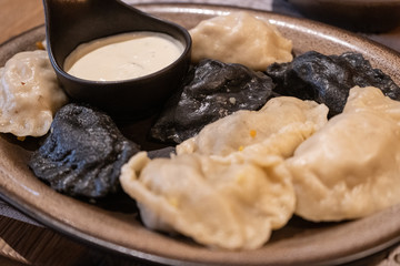 Traditional polish dumplings perogi on a plate accompanied with a white garlic sauce