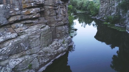 Snaky brook flowing between several stony rocks in the evening in summer