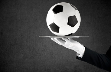 Waiter that holds a tray with soccer ball. Concept of first class service on soccer