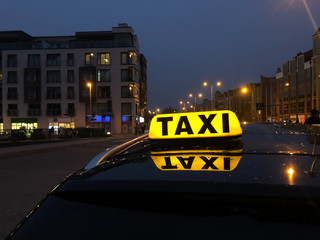 Car with the yellow TAXI sign on the roof  at night. Concept of official transportation business,...