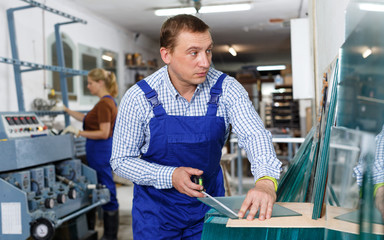 Male glazier measuring glass with tape measure