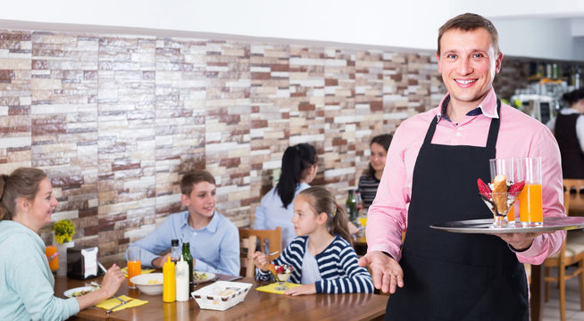 waiter warmly welcoming guests to cozy family cafe