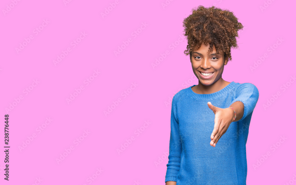 Wall mural beautiful young african american woman over isolated background smiling friendly offering handshake 