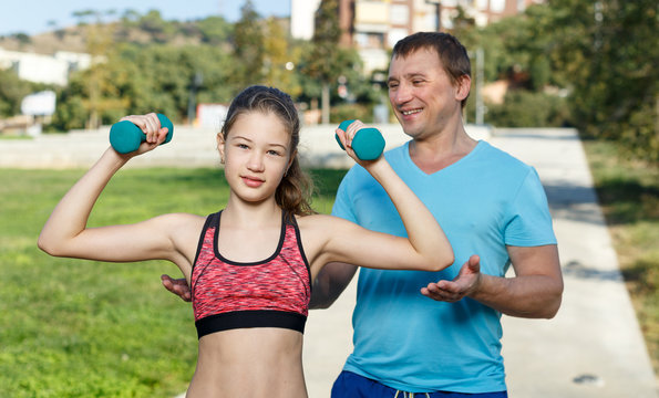Man with girl during workout with dumbbells
