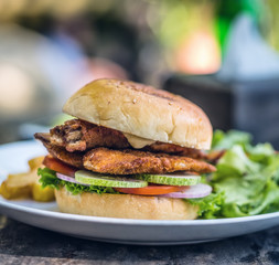 street food fishburger with fish cutlet and vegetables on white plate.