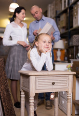 Positive girl stading with curbstone in furniture shop