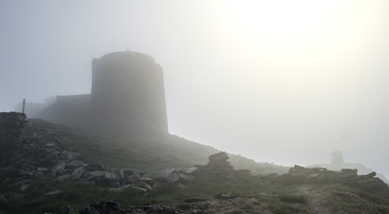 Mist mountain landscape with old abandoned observatory on mount Pip Ivan in Carpathian mountains