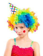 Fototapeta na wymiar Portrait of little sad girl in clown wig and birthday hat with red spots on her cheeks isolated on white background