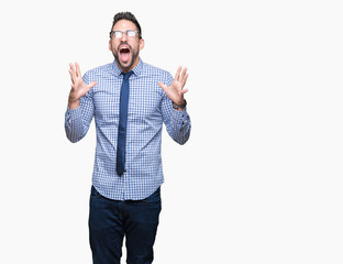 Young business man wearing glasses over isolated background crazy and mad shouting and yelling with aggressive expression and arms raised. Frustration concept.