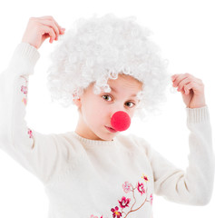 Lovely little girl in white voluminous clown wig and red nose posing in front of camera isolated on white background