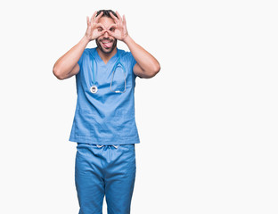 Handsome young doctor surgeon man over isolated background doing ok gesture like binoculars sticking tongue out, eyes looking through fingers. Crazy expression.