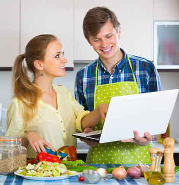 Couple with laptop at kitchen.