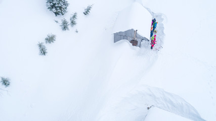 Aerial view of tourists getting ready for extreme hiking in the mountains. Tourists standing near lonely hut in mountains surrounded with bunch of snow
