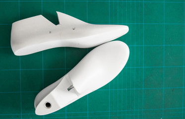 Two white plastic last shoe on rubber secondary cut cutting mat, The equipment used for shoe design.