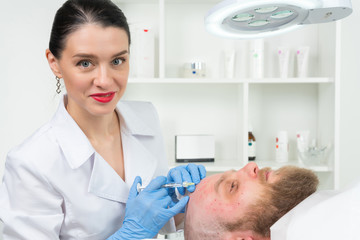 Fototapeta premium The doctor cosmetologist makes the Rejuvenating facial injections procedure for tightening and smoothing wrinkles on the face skin of a men in a beauty salon.Cosmetology skin care.