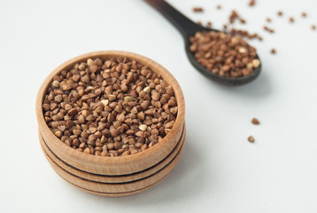 buckwheat seeds in wooden bowl and spoon. isolated on white
