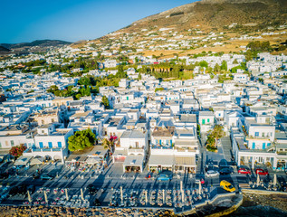 Fototapeta premium Cozy resort town by the seaside, Paros, Greece. Bird's eye view of traditional white houses at sunset