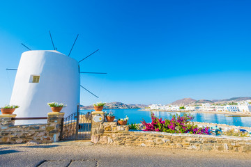 Old white windmill on the cliff in front of water and beautiful blue sky at sunny day, Paros, Greece