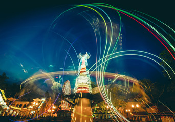 Abstract bright neon light trails of carousels in luna park at twilight