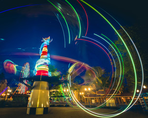 light trails of carousels in amusement park at twilight