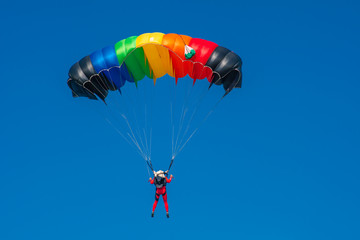 Skydiver with parachute colored in LGBT flag colors. Copy space area