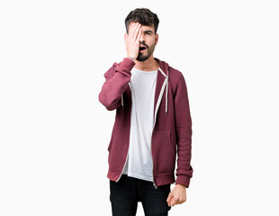 Young handsome man over isolated background Yawning tired covering half face, eye and mouth with hand. Face hurts in pain.