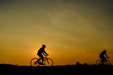 Obraz premium Man ride bicycle on sunset background