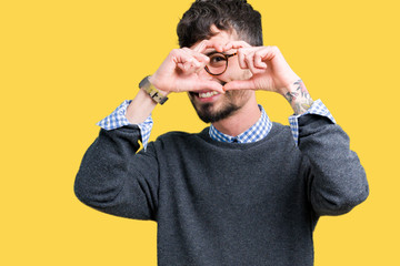 Young handsome smart man wearing glasses over isolated background Doing heart shape with hand and fingers smiling looking through sign