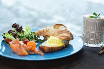 Tasty croissant sandwich with salmon on plate