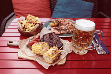 Grilled corn, hot bbq ribs with mug of lager beer, toned