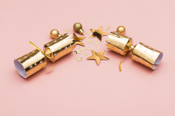 Christmas crackers. luxury gold festive cracker on a pastel pink background