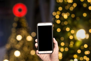 Holding a Smartphone on Golden Bokeh of a street with people on christmas day or New year