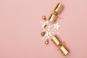 Christmas crackers. luxury gold festive cracker on a pastel pink background
