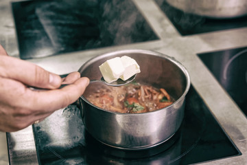 Chef is adding butter to a dish, toned