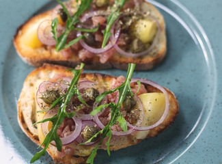 Italian bruschetta with chopped onion, fish, capers and balsamic vinegar