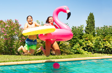 Cute boy and girl jumping into the swimming pool