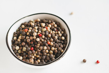 Various kinds of pepper seeds in a white bowl on a white background. Macro photography.