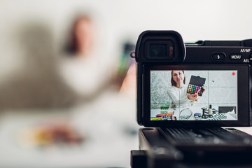 Young woman professional beauty vlogger or blogger recording make up tutorial using camera and...