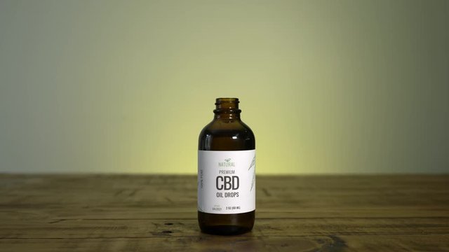 Person takes dropper out of bottle of CBD oil to administer medication.