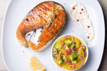 Grilled salmon, salad with oranges and avocado. Close-up, selective focus.