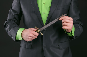 Dagger knife in a gangster hands on a black background.