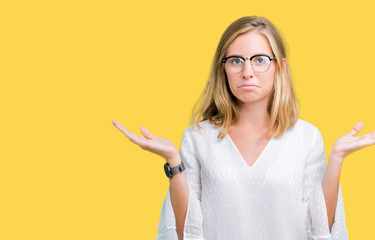 Beautiful young woman wearing glasses over isolated background clueless and confused expression...