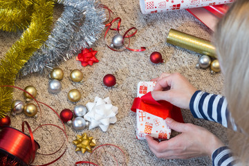 Woman prepare Christmas present with paper and red ribbon