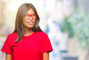 Young asian woman wearing glasses over isolated background looking away to side with smile on face, natural expression. Laughing confident.