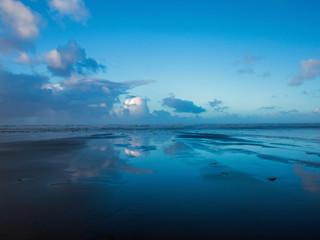 moody blue sky and cloud reflections on Westward Ho! beach in Devon , England