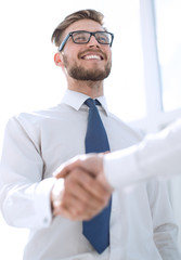 close up.a smiling employee shaking the hand of his colleague